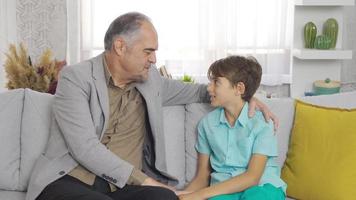el abuelo triste pasa tiempo con su nieto. el abuelo, que pasa tiempo y charla con su nieto en casa, está triste.