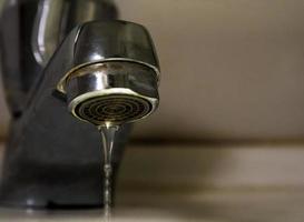 Leaking water drops from old rust and stained faucet photo