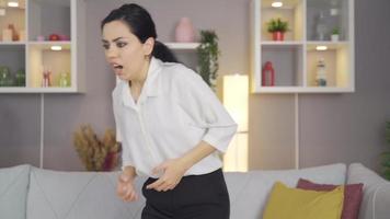 Woman having heart attack at home. Young woman sitting at home and standing up and holding her heart back and expression of pain and fear on her face. video