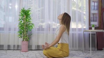 mujer haciendo yoga en casa con los ojos cerrados. mujer joven meditando en casa.