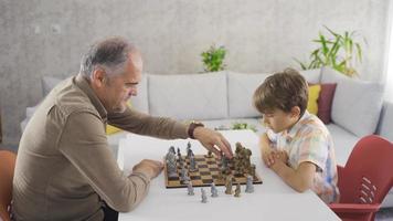 batalla de ajedrez con el abuelo. anciano y su nieto jugando al ajedrez en casa.