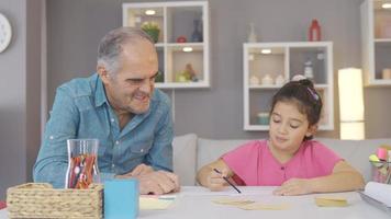 opa senior Mens lezing een boek met zijn kleinzoon. opa aan het studeren met zijn kleinzoon in notitieboekje en boek. video