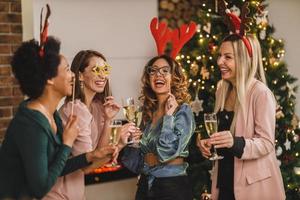 Four Multiethnic Female Friends Having Fun And Make Toast As They Celebrate At Home Christmas Party photo