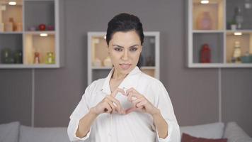 Attractive woman making heart at camera. Happy woman looking at camera and smiling making heart. video