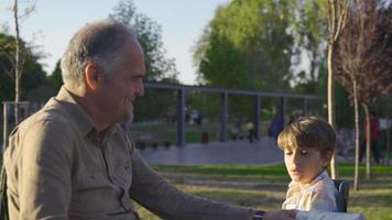 abuelo y nieto se llevan bien y pasan el tiempo. el abuelo está charlando con su nieto al aire libre. video