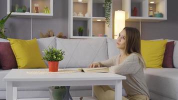 femme lisant un livre à la maison. femme assise sur le sol à la maison en lisant un livre. video