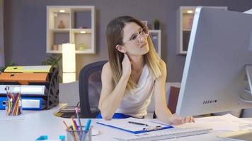 Business woman working in home office has a sore neck. The woman working at the desk works for a long time and her neck is stiff and starts to hurt. video