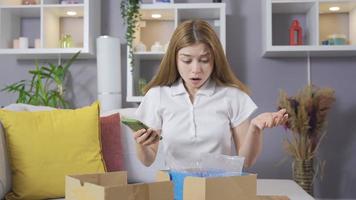 la mujer está abriendo una caja en casa y no está contenta. la mujer que abre la caja de carga no está contenta y ha llegado el artículo equivocado. video