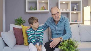 The grandfather motivates his grandson and improves his morale. Grandfather and grandson chatting at home. video