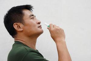 Asian man uses inhaler to smell  for relieve dizzy and faint symptoms. Concept , health problem, sickness and remedy. Increases freshness, reduces dizziness and stuffy nose. self take care. photo