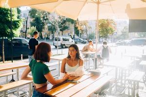 Two pretty girlfriends talking while sitting in a bar outdoors photo