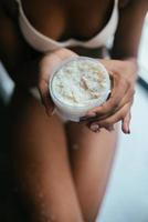 Black-skinned model dressed in underwear holds a jar with a scrub photo