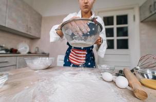 Woman sifting flour through sieve. Selective focus. photo