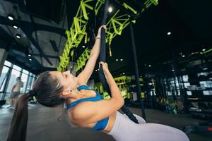 Young woman is climbing a rope in the gym photo