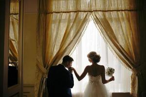 bride and groom standing in front of window photo