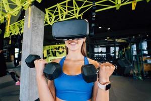 Woman wearing glasses of the virtual reality exercising with dumbbells photo