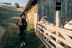 A young beautiful woman near a pen with goats photo