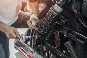 revisión mecánica de motocicletas y cambio de amortiguadores traseros motocicleta scooter en garaje, concepto de reparación, mantenimiento y servicio de motocicletas foto