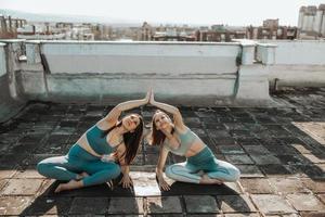 dos mujeres haciendo yoga al aire libre en una terraza en la azotea foto