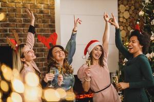 cuatro amigas multiétnicas divirtiéndose y bailando en casa fiesta de navidad foto