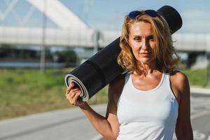 Portrait Of Woman With Rolled Up Exercise Mat photo