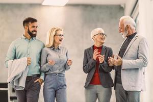 un grupo de empresarios confiados caminando por el pasillo de la oficina y discutiendo entre ellos foto