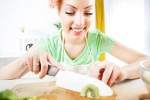 mujer joven cortando kiwi foto