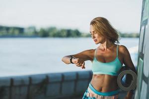 mujer mirando un reloj inteligente después de entrenar cerca del río foto