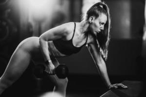 mujer musculosa haciendo entrenamiento de espalda con pesas en el gimnasio foto