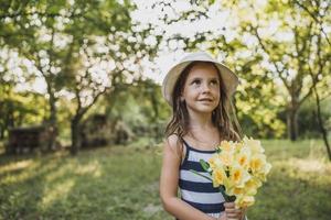 niña con ramo de narcisos en la naturaleza foto