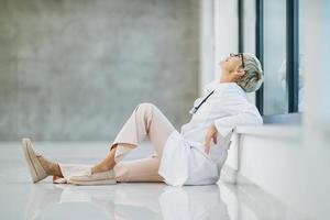 A Tired Female Doctor Looking Worried During Quick Break In An Empty Hospital Hallway photo