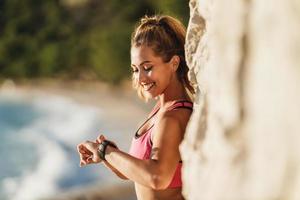 Woman Checking Progress And Looking Heart Rate On Smart Watch During Training Near The Sea photo