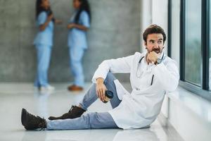 A Worried Doctor Having Coffee Break In An Empty Hospital Hallway photo