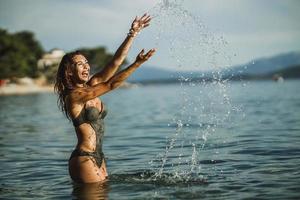 mujer chapoteando en el agua del mar y divirtiéndose en las vacaciones de verano foto
