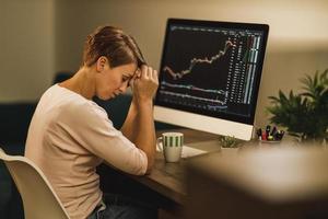 Woman Experiencing Stress During A Late Night Analyzing Crypto Graph From Home photo