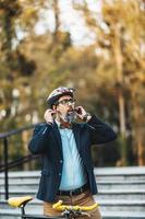 un hombre de negocios poniéndose casco de bicicleta en la cabeza e yendo a trabajar foto