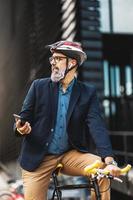 A Businessman Using A Smartphone While Traveling To Work With A Bike photo