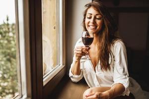 una mujer bebiendo vino tinto en casa foto