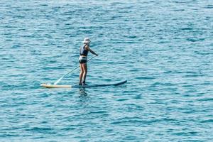 niño remando en sup o stand up paddle board en el mar océano foto