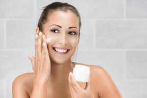 Young Woman Putting Face Cream photo