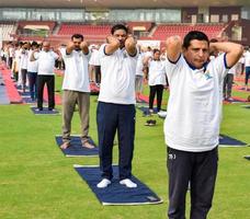 New Delhi, India, June 21 2022 - Group Yoga exercise session for people at Yamuna Sports Complex in Delhi on International Yoga Day, Big group of adults attending yoga class in cricket stadium photo