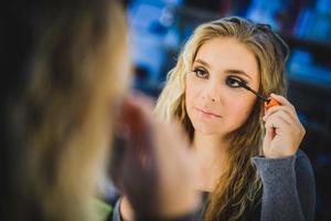 Cute Girl In Front Of Mirror Applying Mascara photo