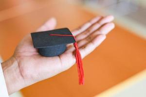 concepto de estudio de negocios de educación de graduación - hombre de negocios o estudiante con gorra de graduación a mano en el día de graduación felicitó a los graduados en la biblioteca de la universidad foto