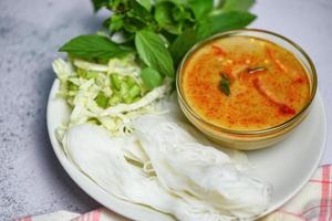 Red curry cuisine asian food on the table - Thai food curry soup bowl with thai rice noodles vermicelli ingredient herb vegetable on white plate photo