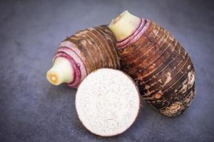 Taro root with half slice on dark background, Fresh raw organic taro root ready to cook photo