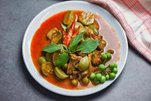 Thai food curry soup on white plate - red curry pork cuisine asian food on the table background photo