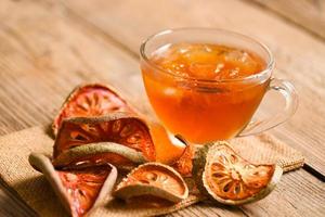 Bael tea on glass with dried bael slices on wooden background, Bael  juice - Dry bael fruit tea for health - Aegle marmelos photo