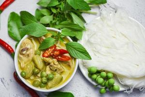 Thai food green curry chicken on soup bowl and thai rice noodles vermicelli with ingredient herb vegetable - asian food on the table photo