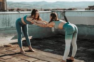 Two Woman Stretching Outdoors While Doing Workout On A Rooftop Terrace photo