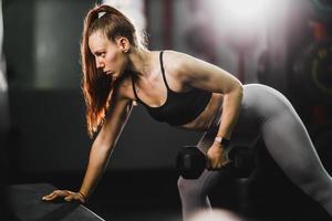 mujer musculosa haciendo entrenamiento de espalda con pesas en el gimnasio foto